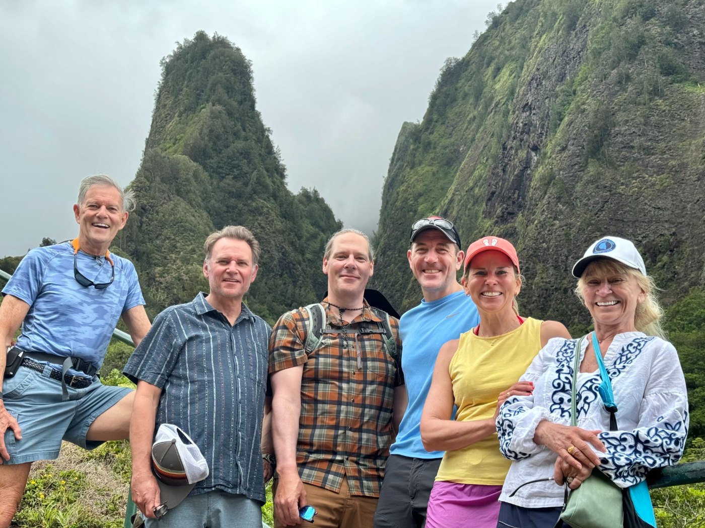 Brett with five friends and partners in front of a green mountain peak
